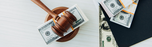 Панорамный снимок банкнот в долларах возле судьи молотка и папки на столе
  - Фото, изображение