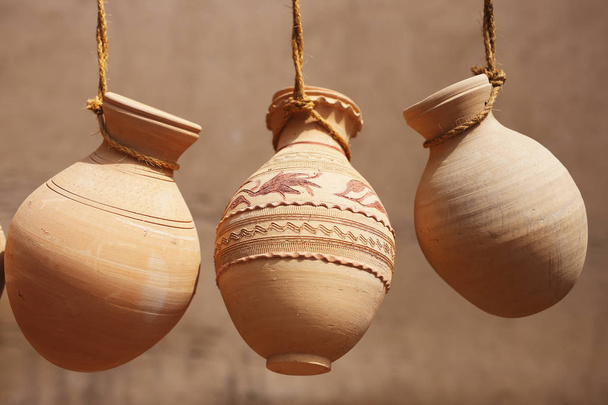 Frascos de cerâmica pendurados em cordas à venda no mercado de Nizwa, Omã
 - Foto, Imagem