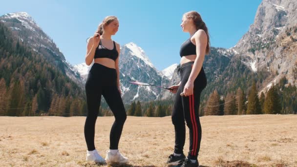 Kaksi nuorta urheilullista naista, joilla on mailat ja jotka puhuvat kentällä - Dolomiitit, Italia
 - Materiaali, video