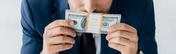 panoramic shot of businessman covering face while smelling dollar banknotes - Фото, изображение