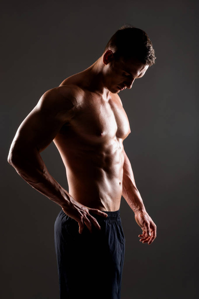 Starker, fitter und sportlicher Bodybuilder mit schwarzem Hintergrund. Sport- und Fitnesskonzept. - Foto, Bild