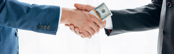 ビジネスパートナーに賄賂を与え、白で隔離された握手をする男のパノラマショット  - 写真・画像