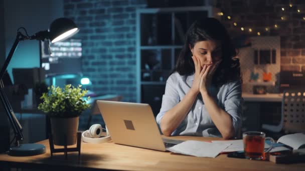 Tired girl working at night in office reading documents suffering from headache - Footage, Video