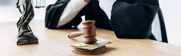 Panoramaaufnahme eines Richters in der Nähe eines Holzgabel mit Geld auf dem Tisch  - Foto, Bild