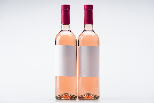 zwei Flaschen Rosenwein mit leeren Etiketten auf weißem Hintergrund - Foto, Bild