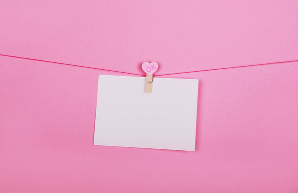 Folhas de papel em branco em uma linha de roupa em um contexto rosa. Corações cor-de-rosa em panos. Dia dos Namorados, conceito do Dia das Mães
. - Foto, Imagem