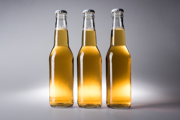 kolme lasipulloa, joissa olut harmaalla pohjalla
 - Valokuva, kuva