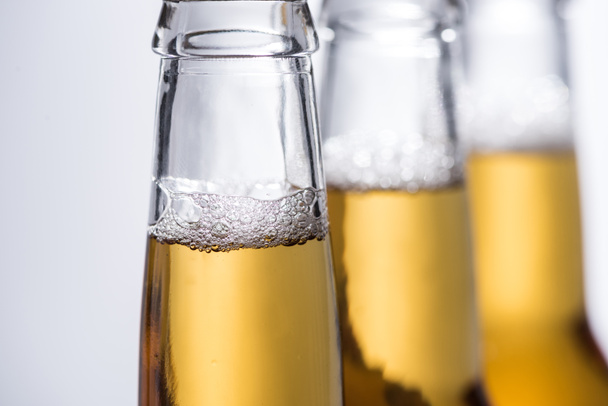 selective focus of beer bottles with bubbles isolated on grey - Photo, Image