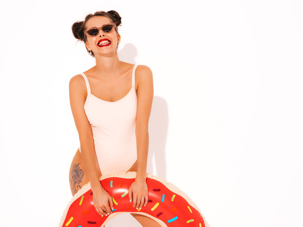 Young beautiful sexy smiling hipster woman with red lips in sunglasses.Girl in summer swimwear bathing suit with donut lilo inflatable mattress.Positive female going crazy.Funny model isolated  - 写真・画像