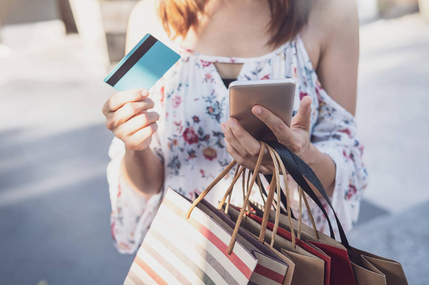 Young woman using smartphone with shopping bags and credit card  - Foto, immagini