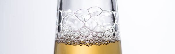 白いパノラマショットで分離された泡でビール瓶のクローズアップビュー - 写真・画像