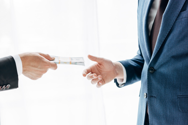 cropped view of man giving cash to business partner on white - Photo, Image