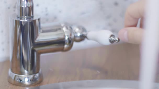 Macro, a mão de alguém move a torneira de água da torneira para abri-la para que a água possa fluir
. - Filmagem, Vídeo
