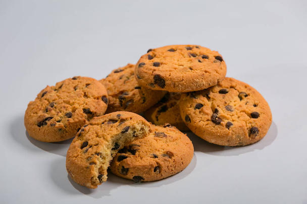 Biscoitos de aveia com pedaços de chocolate são definidos em um fundo branco
. - Foto, Imagem