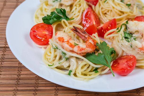 Pasta de espaguetis cocidos con colas de camarón y tomates cherry de cerca
 - Foto, imagen