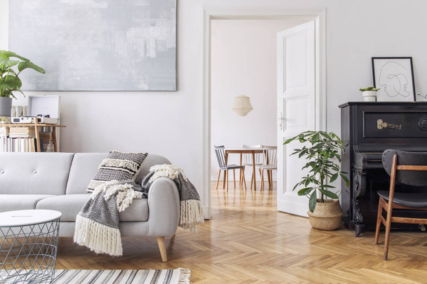 Moderní skandianvijská výzdoba obývací místnosti s návrhovou pohovkou s elegantními přikrývkami, stolek na kávu a stánek na bílé stěně. Hnědá dřevěná parkety. Koncept minimalistického interiéru s klavírem. S předstíranou - Fotografie, Obrázek