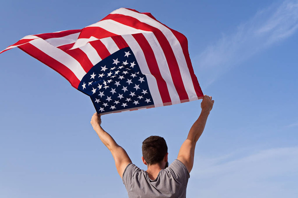 Homme par derrière avec les mains levées et agitant le drapeau américain
 - Photo, image