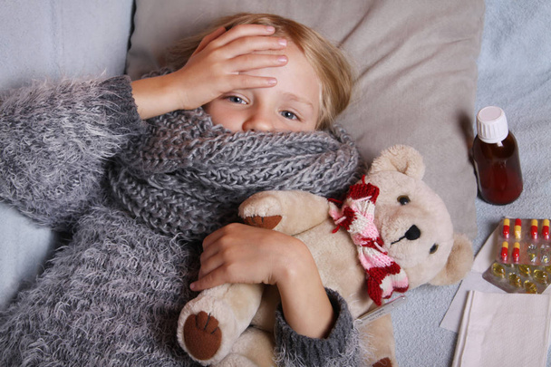 Chora mała dziewczynka leżąca w łóżku z zabawką - Zdjęcie, obraz