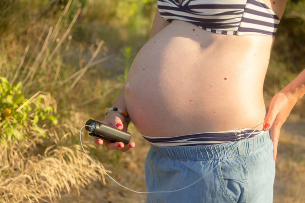 Une femme diabétique enceinte avec une pompe à insuline dans une forêt. Elle...
 - Photo, image