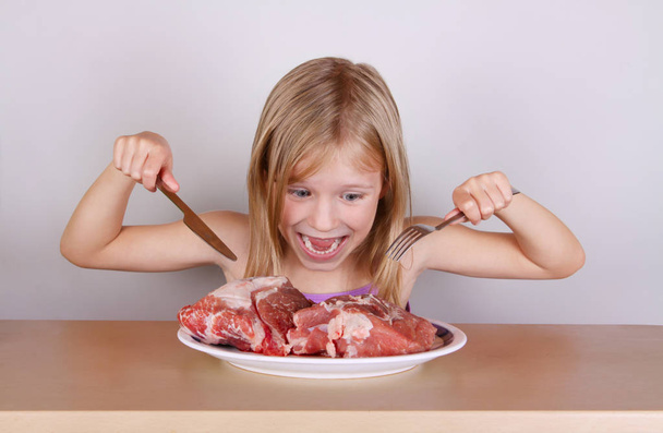 ragadozó Keto Paleo étrend koncepció-kis szőke lány eszik nyers húst    - Fotó, kép
