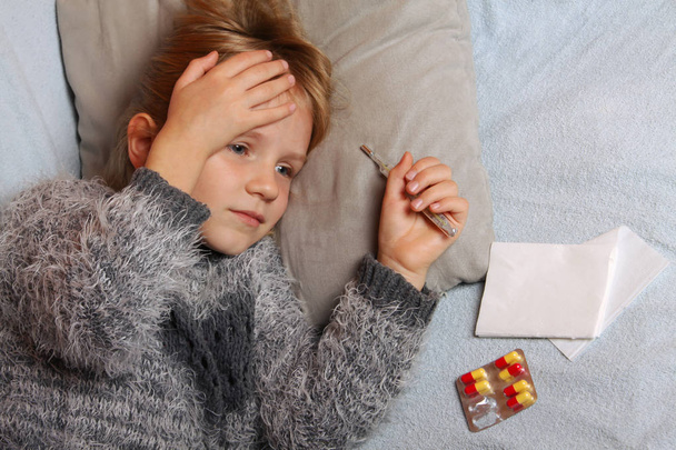 Nemocný děvče ležící v posteli s teploměrem a léky - Fotografie, Obrázek