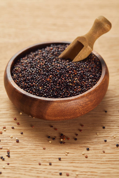black quinoa seeds in wooden bowl with spatula - Fotoğraf, Görsel