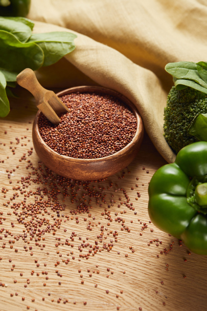 quinoa rouge dans un bol en bois avec spatule près de serviette beige et légumes verts mûrs
 - Photo, image