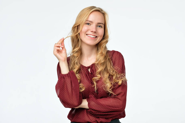 Счастливая блондинка с длинными волосами в красной рубашке улыбается, глядя в камеру
 - Фото, изображение