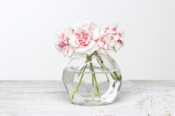 Bouquet of pink carnations in small glass vase. - Zdjęcie, obraz