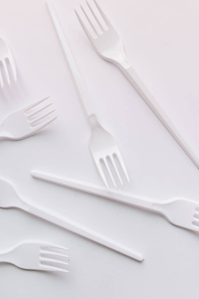 set van witte plastic vorken platte lay op witte achtergrond - Foto, afbeelding