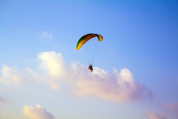 Парагвайдер літає над морем. Парагвайдер літає барвистим парагвайдером у блакитному небі
. - Фото, зображення