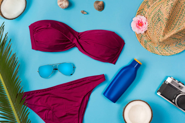 Beach theme on the blue background. Sunglasses, hat, sunscreen, swimsuit, on the blue background. Top view. - Zdjęcie, obraz