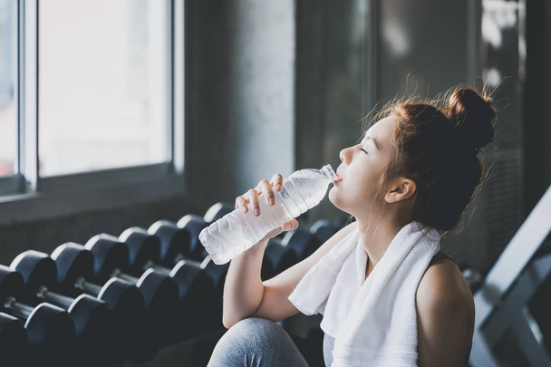 Fitness woman drinking water in gym - 写真・画像
