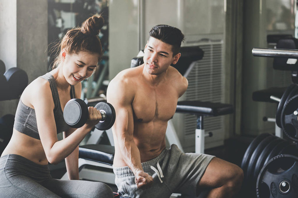 Fitness man and woman doing exercise in gym - Photo, Image