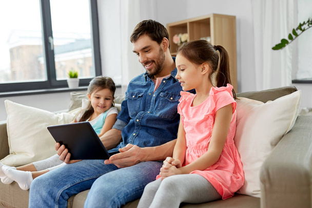 happy father and daughters with tablet pc at home - Foto, Imagen