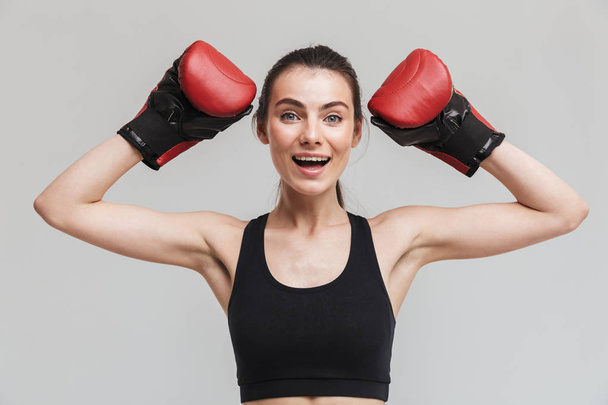Young sport fitness woman boxer isolated over grey wall background make exercises in gloves. - Φωτογραφία, εικόνα