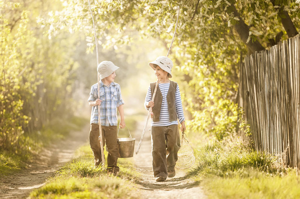 Boys go fishing with fishing rods on a rural street - Photo, Image