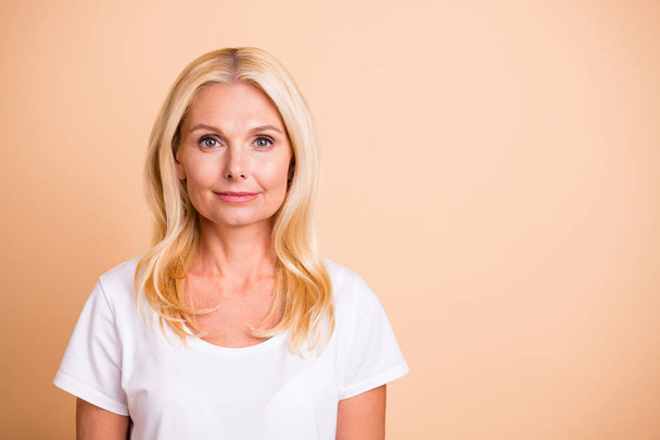 Photo of middle age lady pretty smiling neat appearance good-looking wear white casual t-shirt isolated pastel beige background - Valokuva, kuva