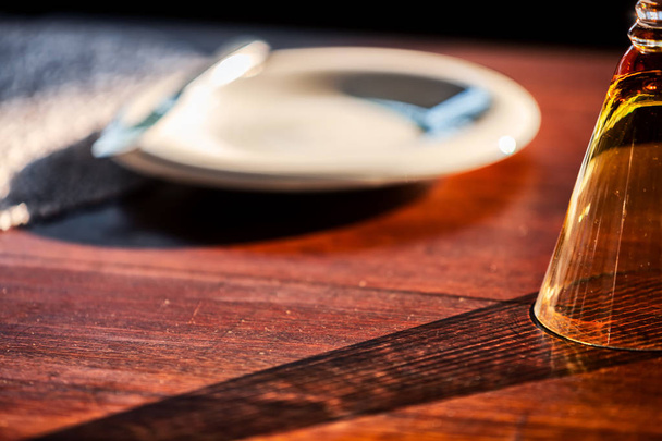 Detalle de cristal sobre mesa de madera de lujoso restaurante con sombras de luz natural
. - Foto, Imagen
