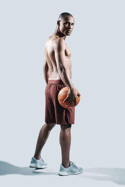 Sport is the way of his life. Full length of handsome young African man in sports clothing looking at camera while standing against grey background - Fotoğraf, Görsel