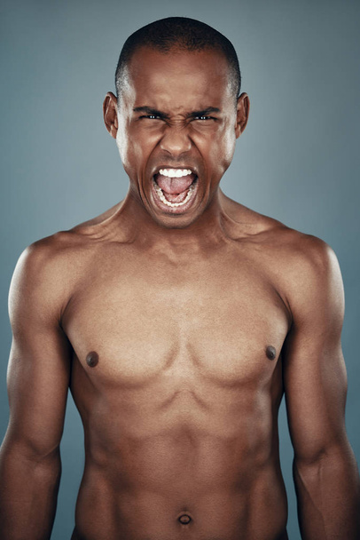 Furious man. Shirtless young African man looking at camera and shouting while standing against grey background - Photo, Image