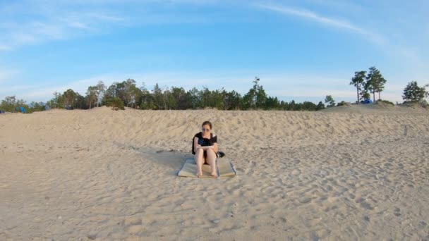 Κορίτσι κάθεται στη θάλασσα ακτή, σε μια αμμώδη παραλία, και ζωγραφίζει - Πλάνα, βίντεο