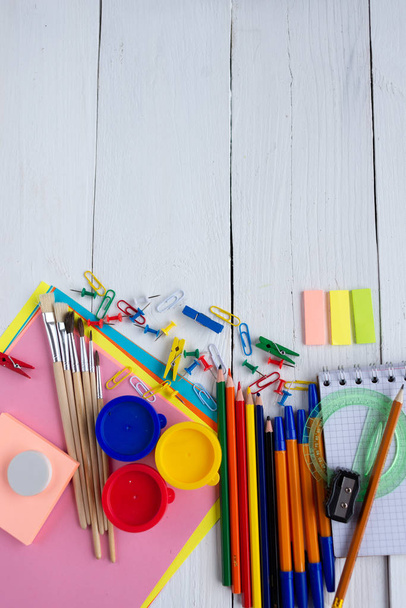 stationery paint brushes color paper pencils laid out on a white wooden background. preparation for school - Foto, Imagen