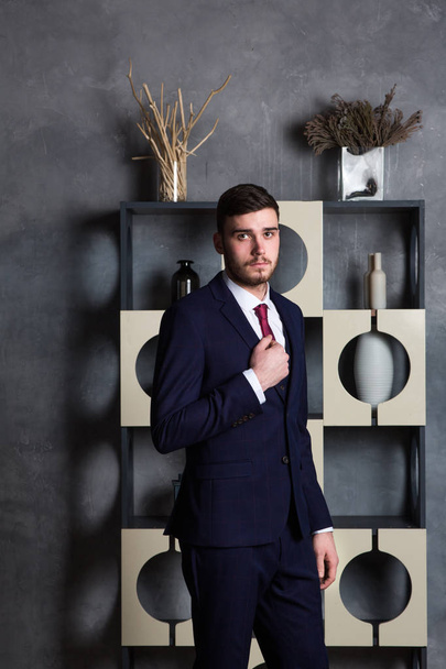 Elegant man in a three-piece suit stands in interior studio - Photo, Image