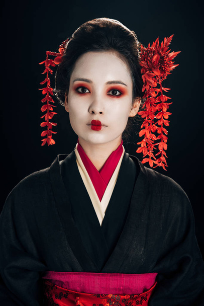 beautiful geisha in black and red kimono and flowers in hair isolated on black - Φωτογραφία, εικόνα