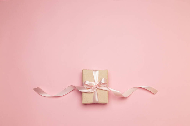 Flat lay top view crafting paper gift on pink background. Minimalism concept. Holiday banner. - 写真・画像