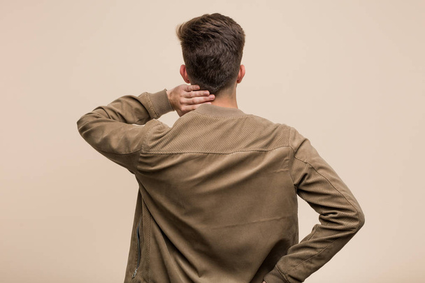 Young caucasian man wearing a brown jacket from behind thinking about something. - Фото, изображение