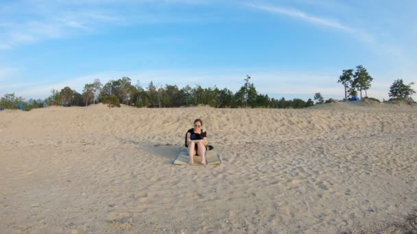 Girl sitting on sea shore, on a sandy beach, and draws - Footage, Video
