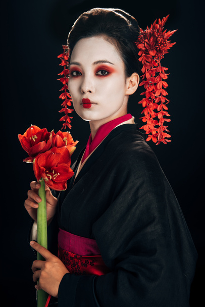 beautiful geisha in black kimono with red flowers isolated on black - Fotó, kép