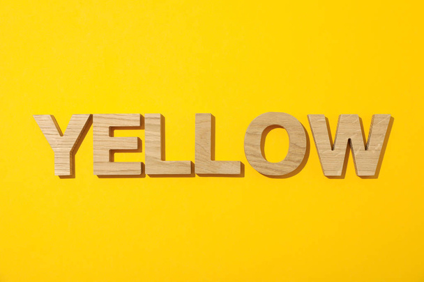 Sana Keltainen säädettyihin puisilla kirjaimilla värillinen tausta
 - Valokuva, kuva